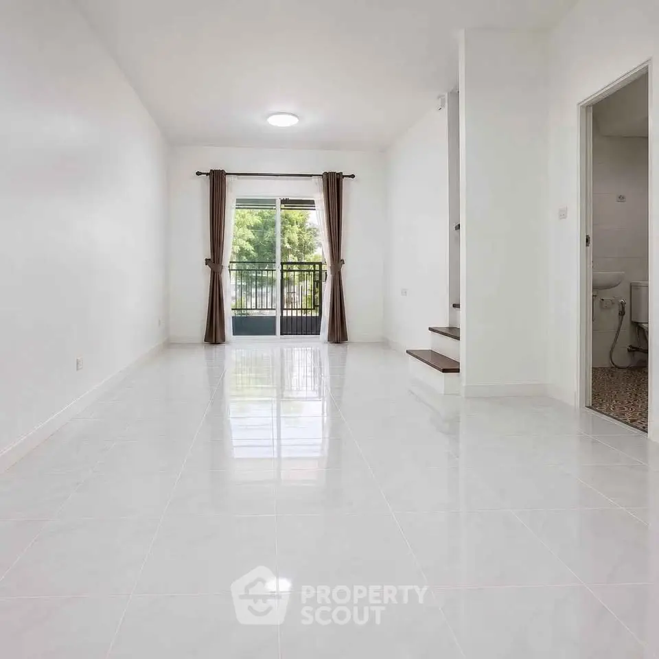 Spacious living room with glossy tile flooring and balcony view