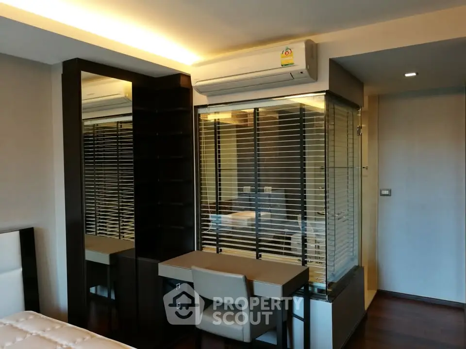 Modern bedroom with sleek design featuring built-in desk and air conditioning unit.