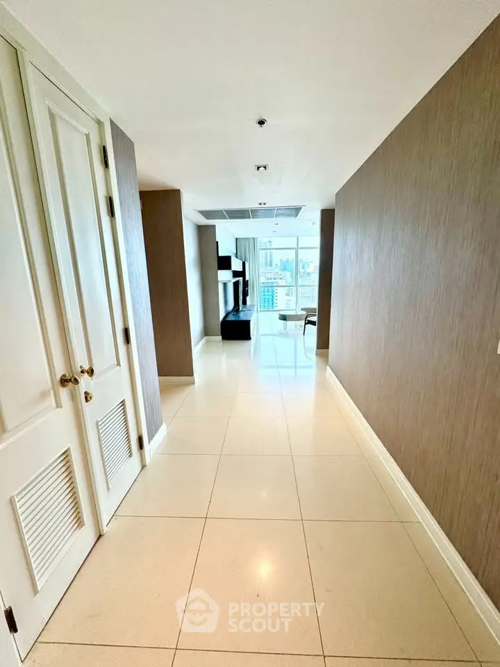 Spacious hallway leading to a bright living area with modern decor and large windows.