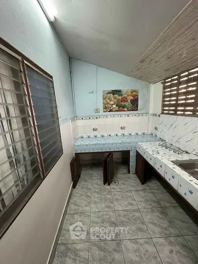 Compact kitchen with tiled countertops and fruit-themed backsplash, featuring a closed layout and gas stove.