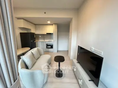 Modern living room with open kitchen, cozy sofa, and sleek TV setup in a stylish apartment.