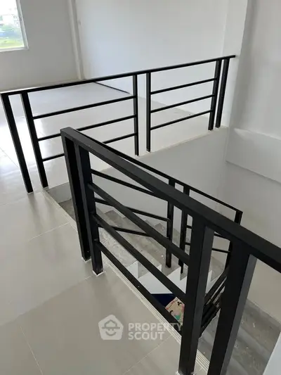 Modern staircase with sleek black railings in a contemporary building interior.