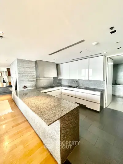 Modern kitchen with sleek white cabinets and granite countertops in open layout design.