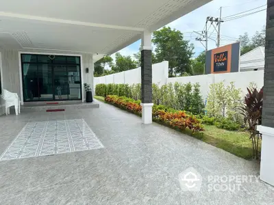 Spacious villa entrance with elegant tiled flooring and lush garden, perfect for a serene living experience.