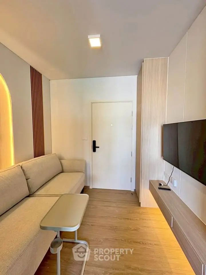 Modern living room with sleek design, featuring a cozy sofa, wall-mounted TV, and stylish lighting.