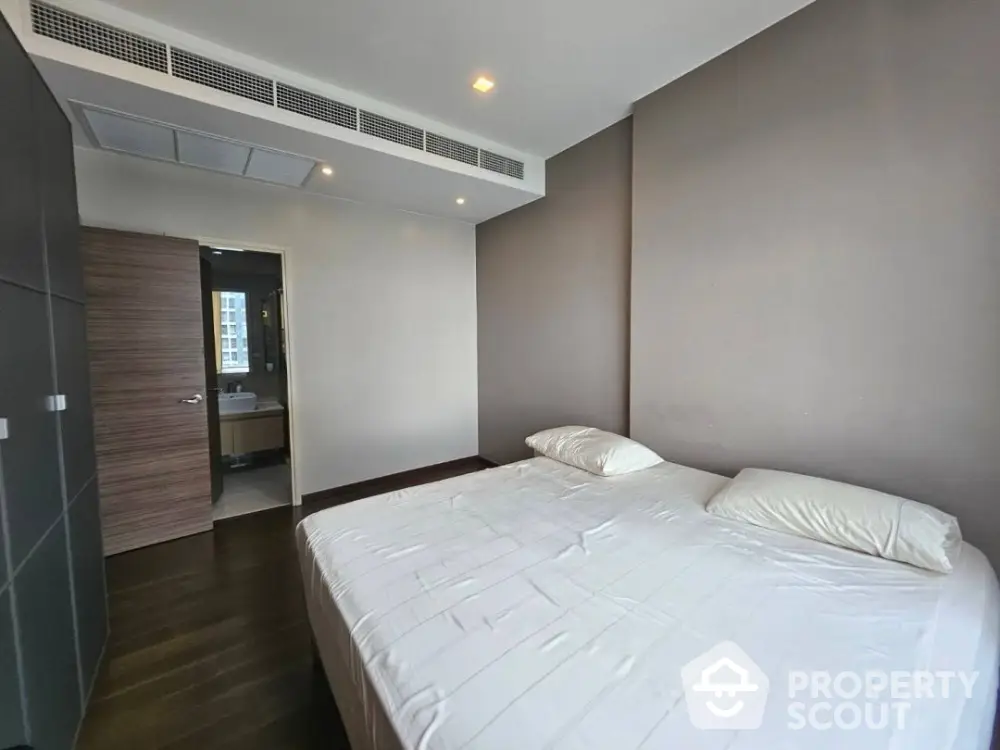 Modern bedroom with minimalist design and ensuite bathroom in a luxury apartment.