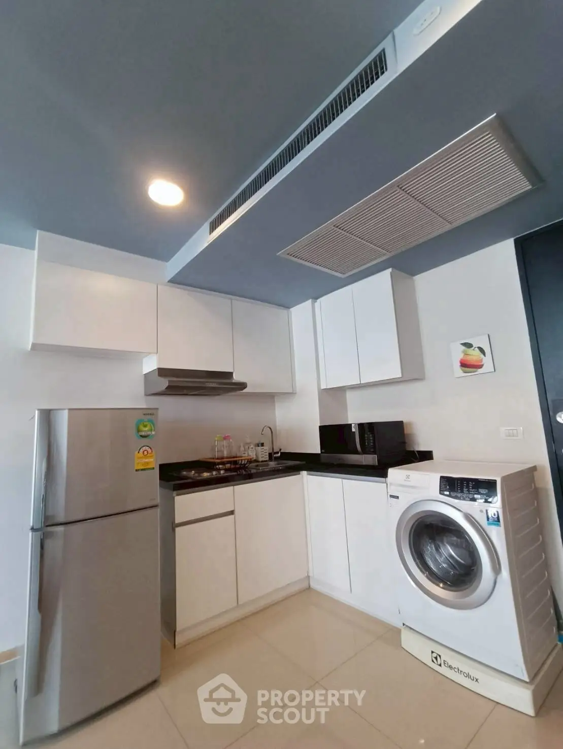 Modern kitchen with sleek cabinets, stainless steel fridge, and washing machine.