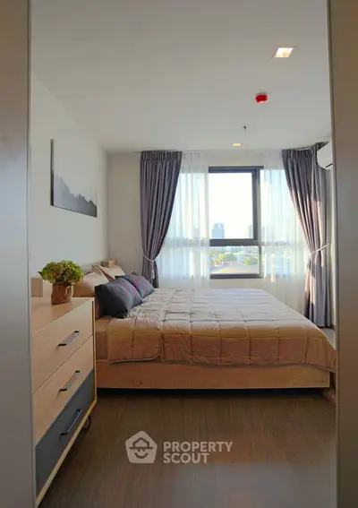 Cozy bedroom with large window and modern decor in a high-rise apartment.