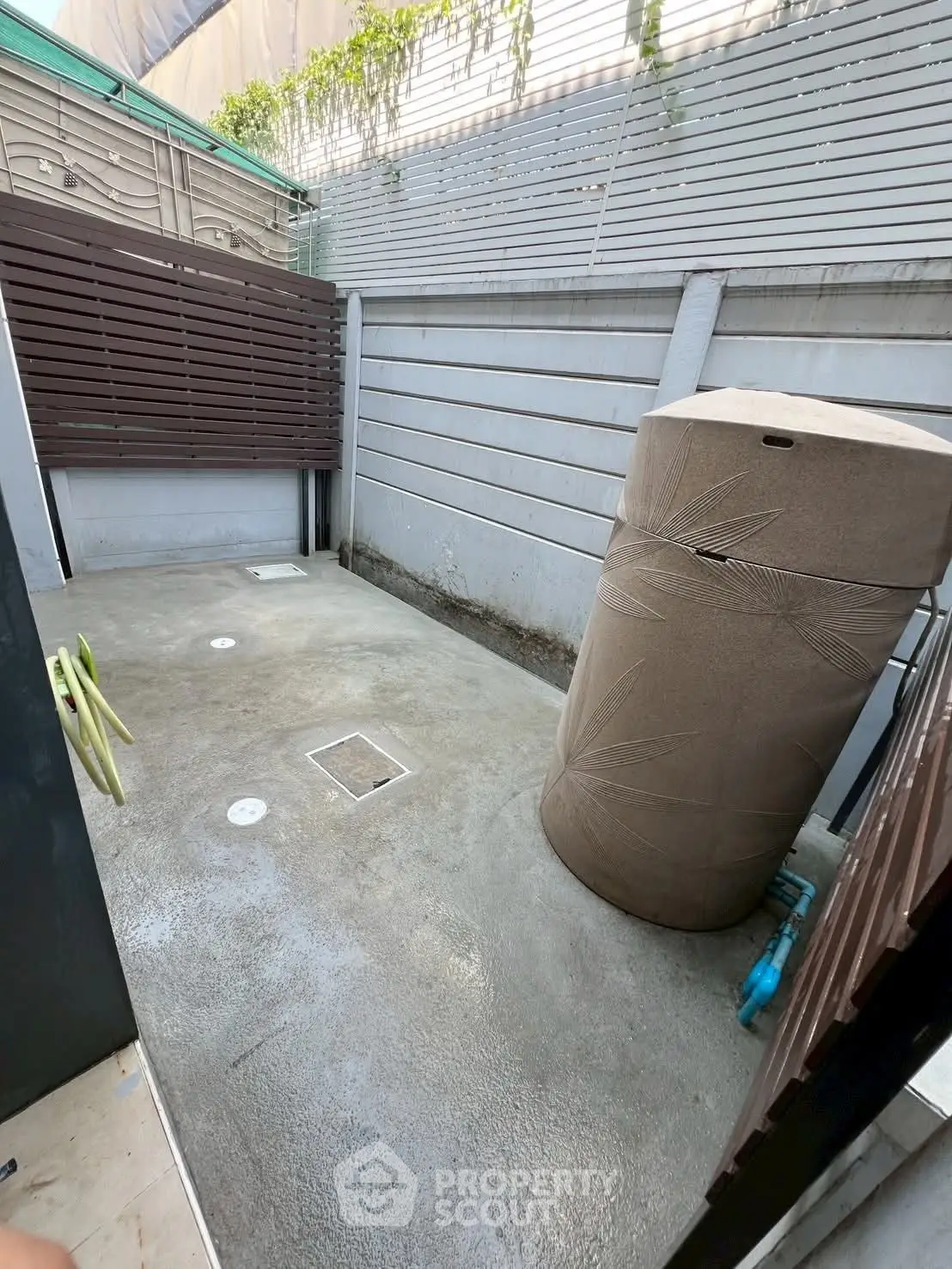 Spacious outdoor utility area with water tank and privacy fencing