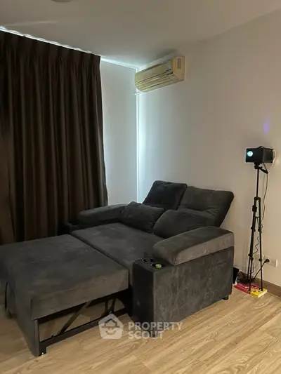 Cozy living room with modern gray sofa and air conditioning, perfect for relaxation.
