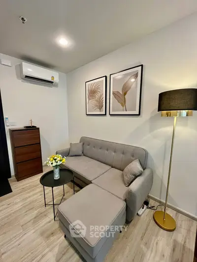 Cozy living room with modern decor, featuring a stylish gray sofa, elegant floor lamp, and chic wall art.