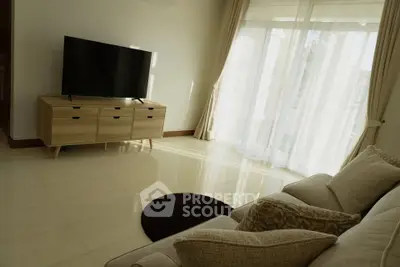 Spacious living room with modern TV setup and elegant curtains