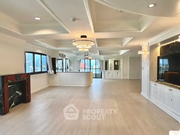 Spacious luxury living room with chandelier and city view, featuring elegant ceiling design and large windows.