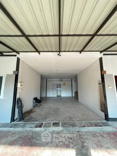 Spacious garage with concrete flooring and metal roof, ideal for storage or parking.