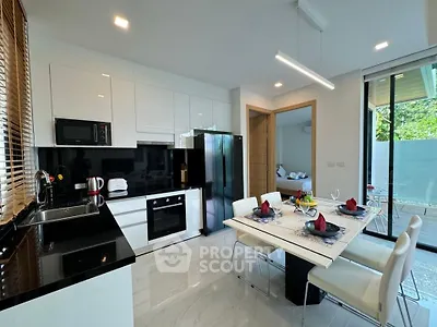 Modern kitchen with sleek black countertops and dining area in bright open layout