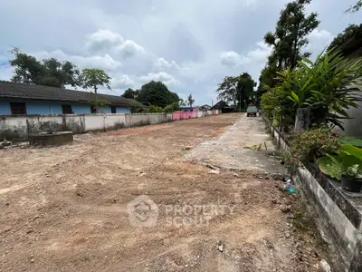 Spacious land plot with potential for development, surrounded by greenery and neighboring houses.