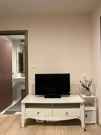 Modern living room with TV and elegant decor, adjacent to a sleek bathroom.