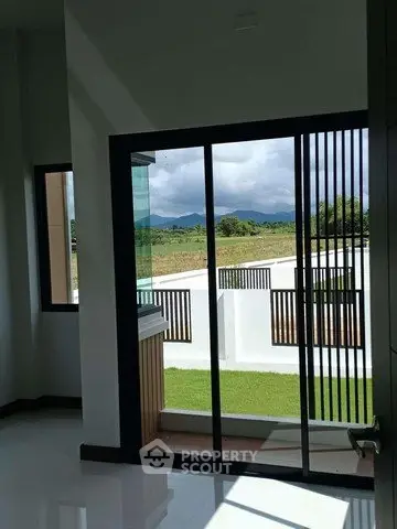 Modern interior with sliding glass doors opening to a scenic view of lush greenery and mountains.