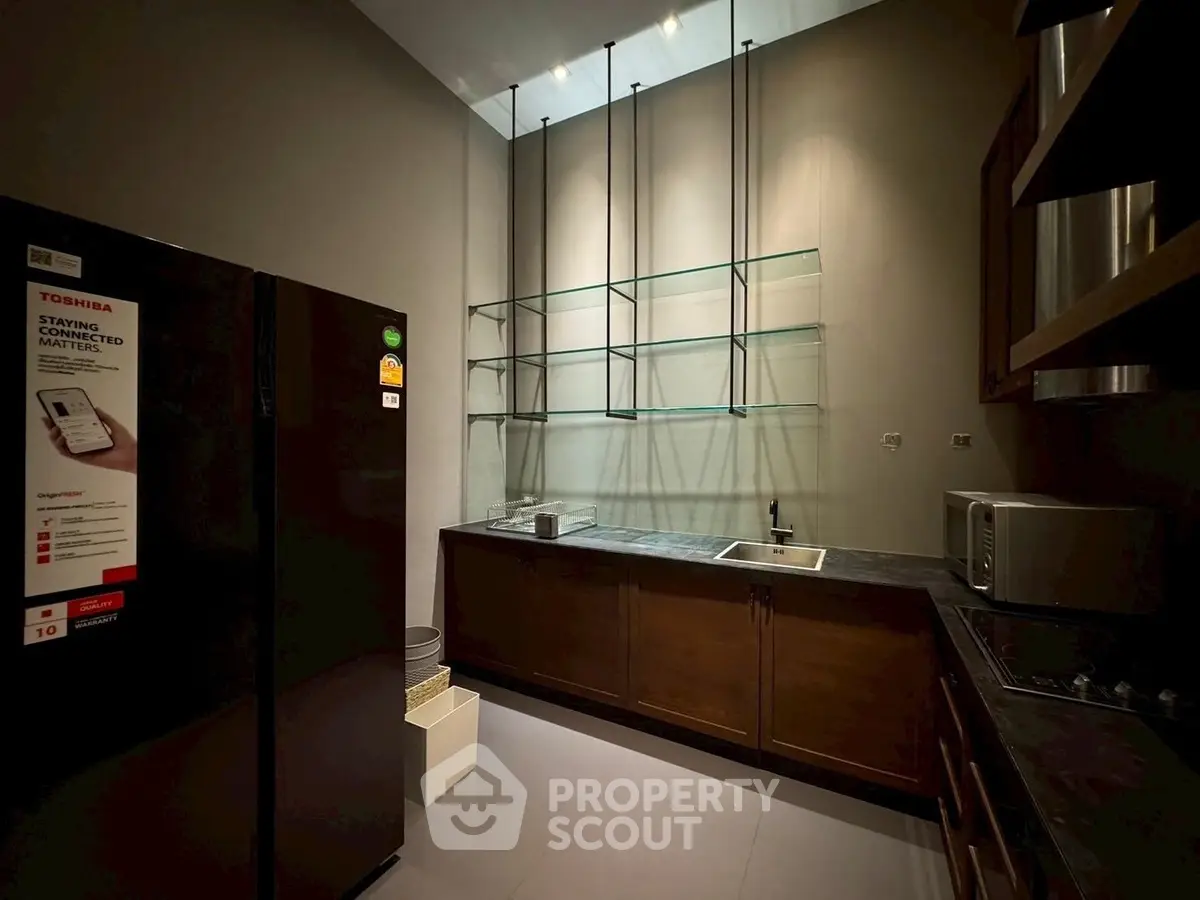 Modern kitchen with sleek cabinetry and high ceilings, featuring a refrigerator and microwave for convenience.