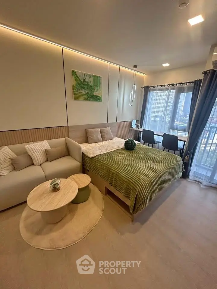 Modern studio apartment with cozy living area and large windows offering city views.