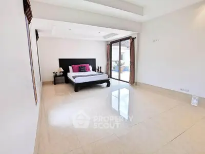 Spacious bedroom with elegant decor and large windows offering natural light.