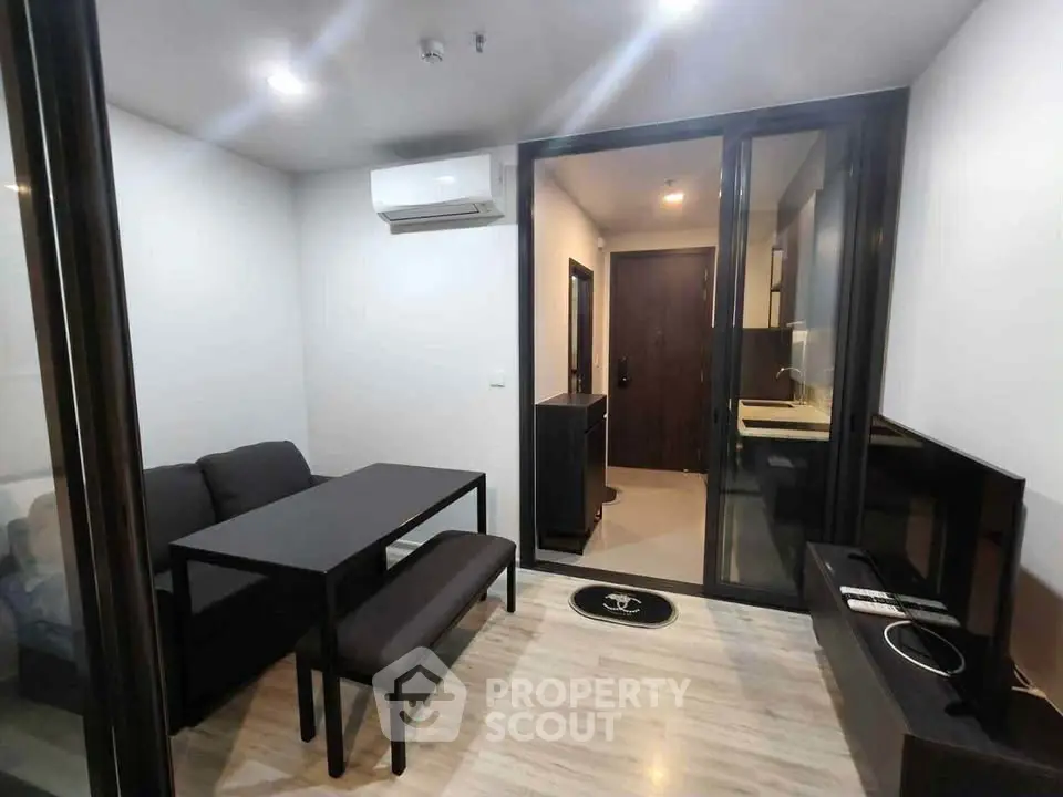 Modern compact living room with sleek furniture and glass partition, ideal for urban living.