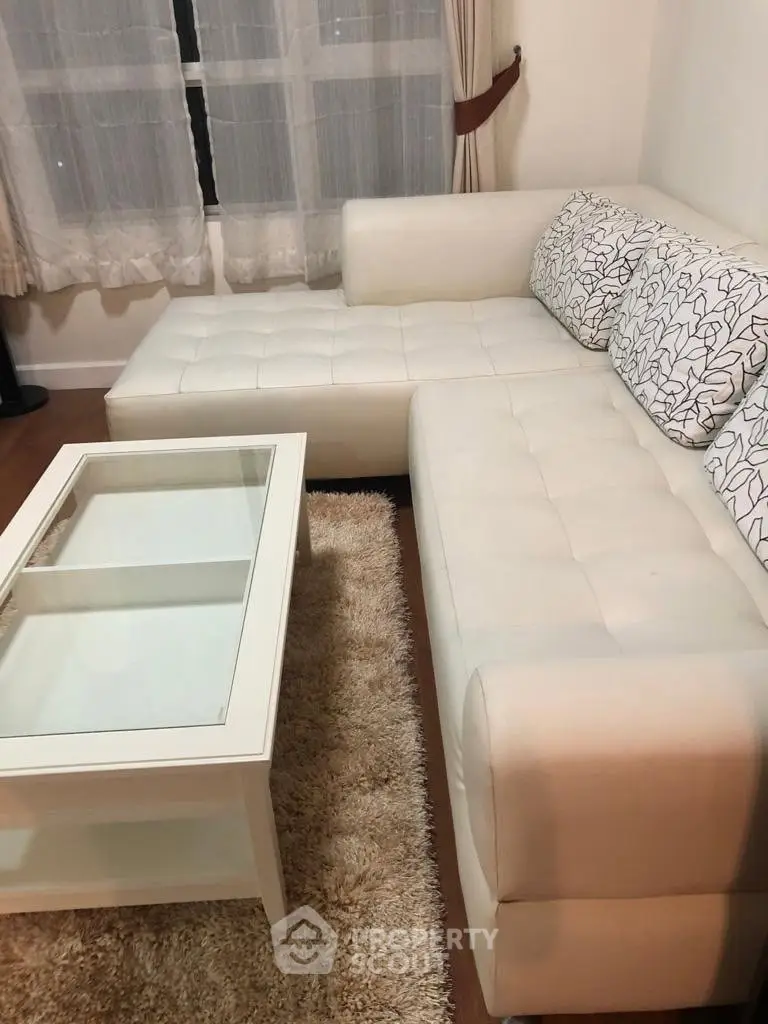 Cozy living room with white sectional sofa and glass coffee table, perfect for relaxation.