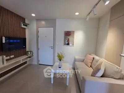 Modern living room with cozy sofa, wall-mounted TV, and stylish decor in a contemporary apartment.