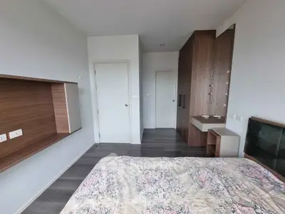 Modern bedroom with stylish wooden accents and floral bedding in a contemporary apartment.
