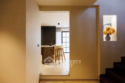 Modern kitchen with open layout and stylish bar stools, featuring elegant lighting and contemporary design.