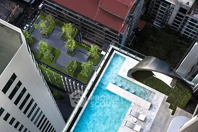 Stunning rooftop pool with cityscape view and lush greenery in a modern high-rise building.