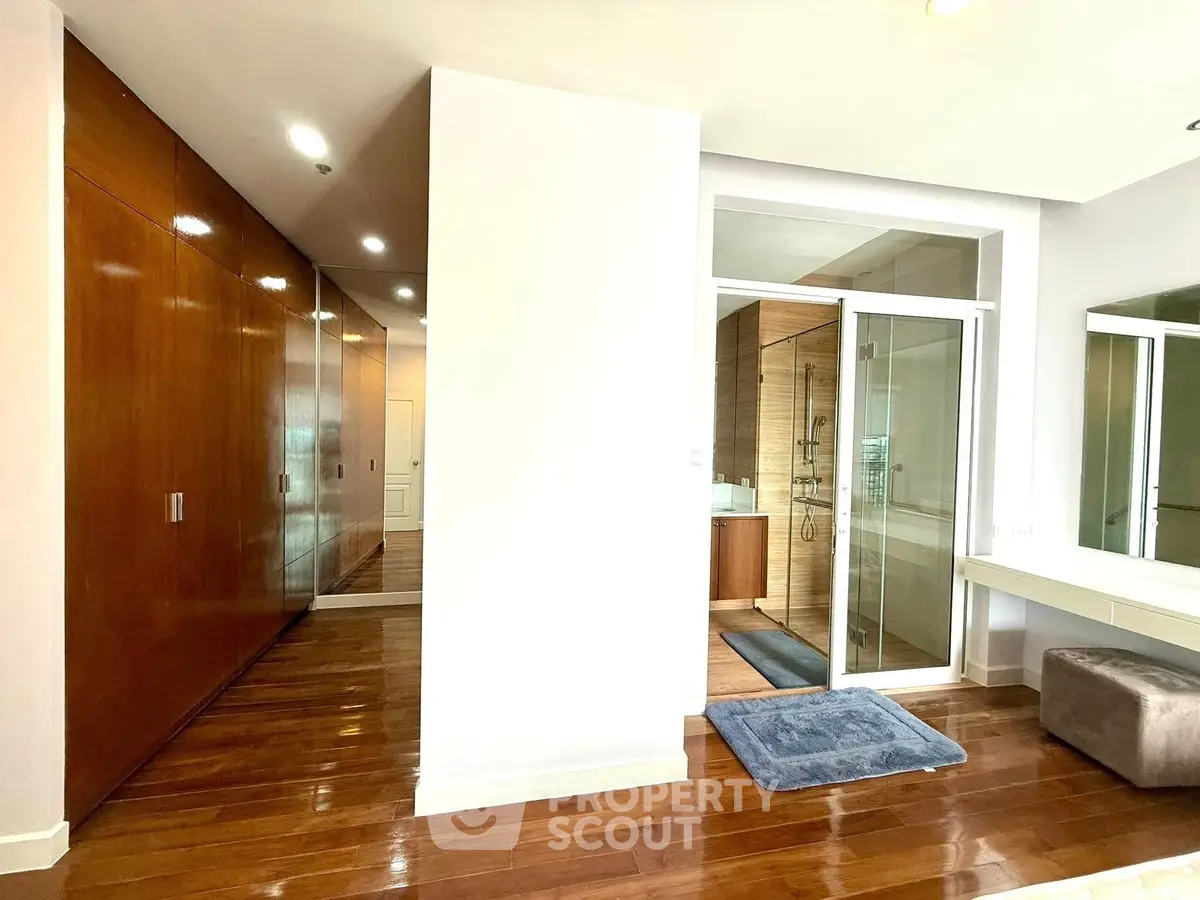 Spacious bedroom with wooden flooring and built-in wardrobe, featuring a modern ensuite bathroom.