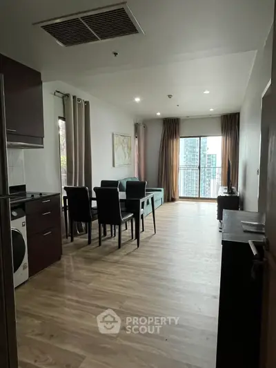 Modern open-plan living room with dining area and city view balcony in a stylish apartment.