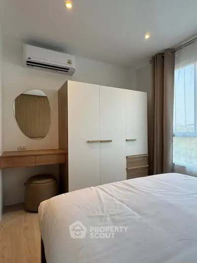 Modern bedroom with stylish wardrobe and air conditioning, featuring natural light and elegant decor.