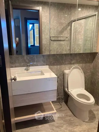 Modern bathroom with sleek fixtures and marble tiles, featuring a spacious shower and elegant vanity.