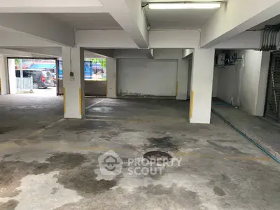 Spacious indoor parking area with multiple parking slots and concrete flooring.