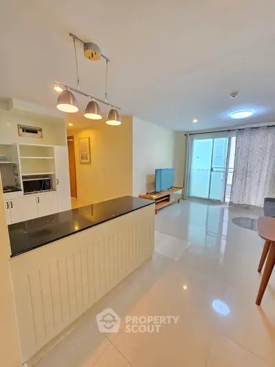 Spacious open-plan living room with modern kitchen and balcony access