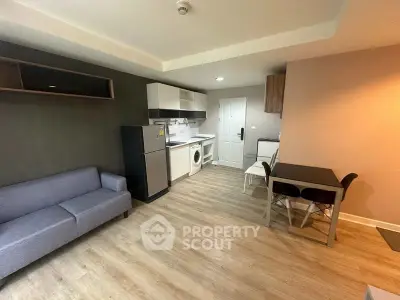 Modern apartment interior with kitchen and living area, featuring sleek furniture and appliances.