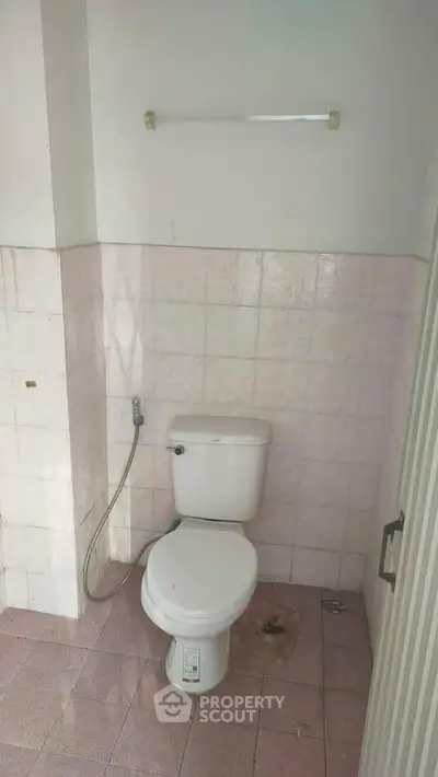 Compact bathroom with tiled walls and floor featuring a standard toilet setup.