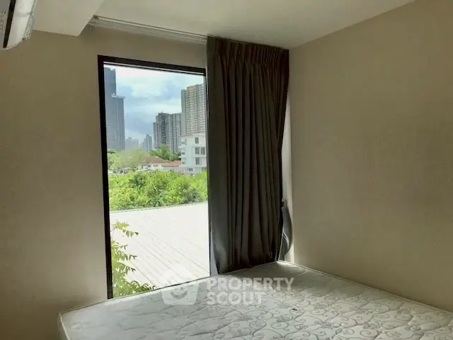 Cozy bedroom with large window offering stunning city view in modern apartment.