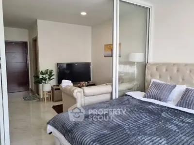 Modern bedroom with plush bed and cozy living area in open layout apartment.