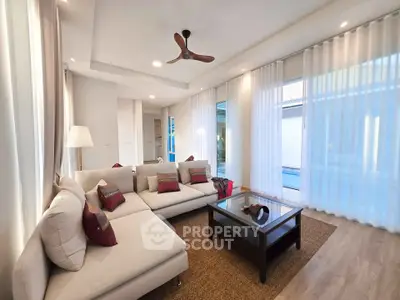 Spacious modern living room with elegant decor and pool view, featuring a cozy sectional sofa and stylish ceiling fan.