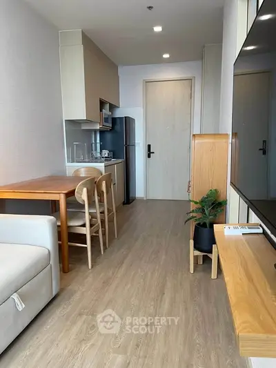 Modern living room with open kitchen, wooden flooring, and stylish furniture in a cozy apartment.