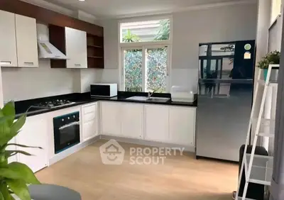 Modern kitchen with sleek appliances and open layout, featuring a gas stove and large fridge.