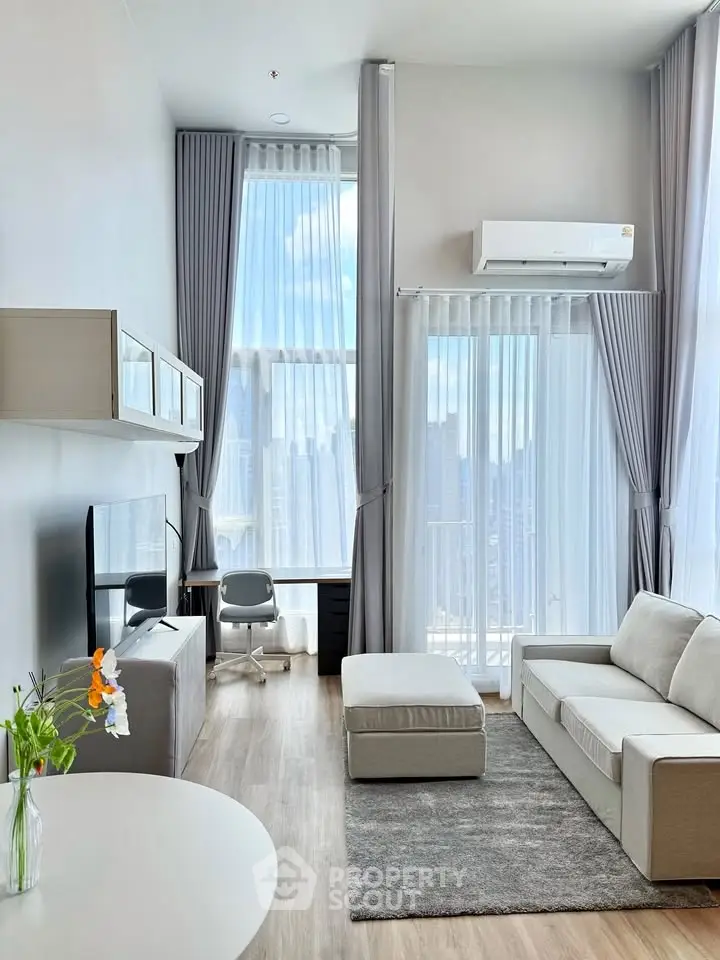 Modern living room with high ceilings, large windows, and stylish furniture in a luxury apartment.