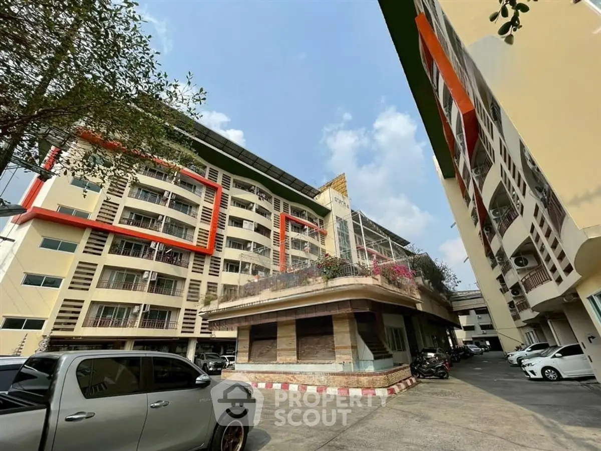 Modern apartment complex with unique architectural design and spacious parking area.