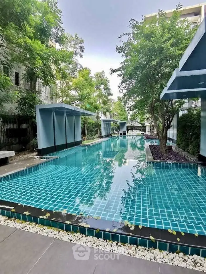 Luxurious outdoor pool surrounded by lush greenery in a modern residential complex.