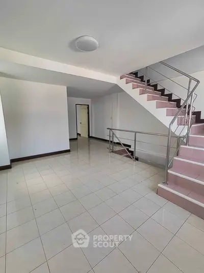 Spacious interior with tiled floor and modern staircase, perfect for versatile living arrangements.