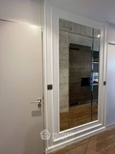 Elegant interior with a large mirrored wall and sleek door, showcasing modern design and spaciousness.