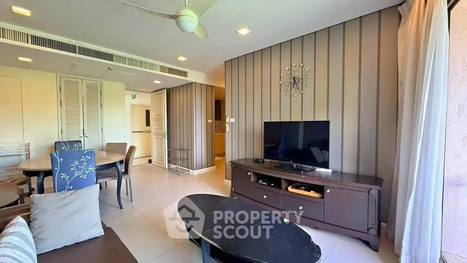Spacious living room with modern decor and natural light, featuring a TV and stylish furniture.